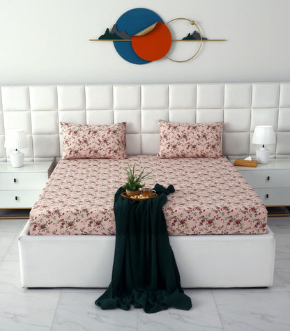 A neatly made bed with a pink floral sheet and matching pillowcases, set in a bright, modern bedroom with a white tufted headboard, white nightstands, and decorative wall art.