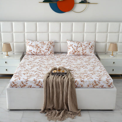 A neatly made bed in a modern bedroom setting, featuring a white tufted headboard, matching white bedding with a brown leaf pattern, two bedside tables with lamps, and a beige throw blanket draped over the foot of the bed.